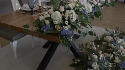 Eleganter Hochzeitstisch, geschmückt mit weißen und blauen Blumenarrangements und üppigem Grün