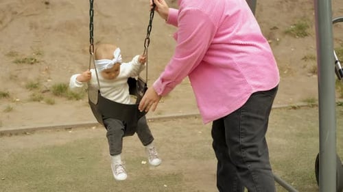 Mama schwingt ihr kleines glückliches Mädchen auf der Schaukel im Park Baby Kind auf dem Spielplatz