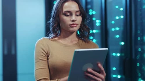 Eine Frau in einem Serverraum verwendet ein Tablet, um komplexe Systeme zu verwalten