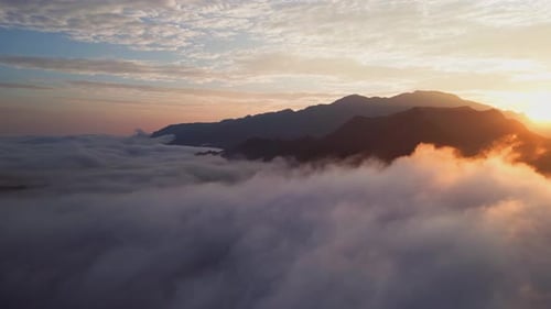 Mountain Sunrise Aerial View with Peaks Rising Above Sea of Clouds and Mist Filled Valleys