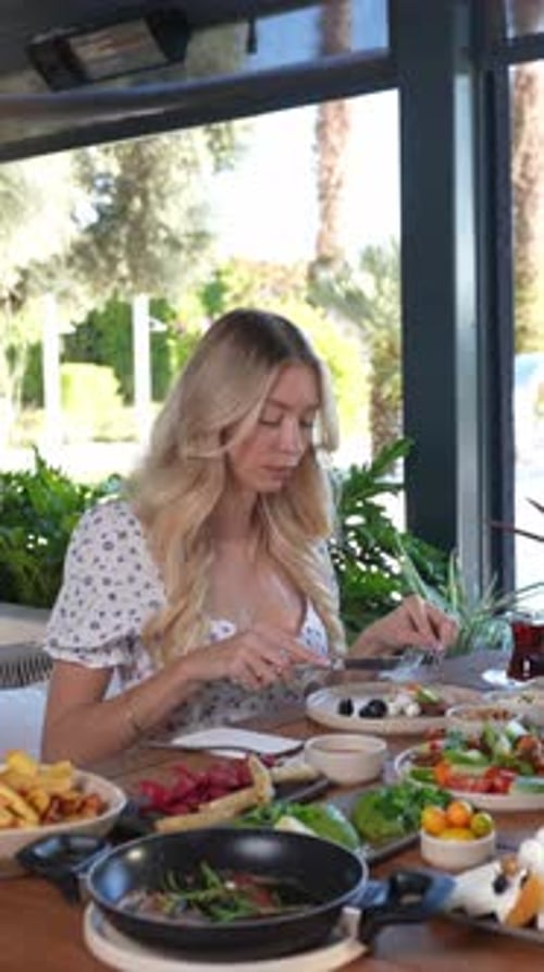 Woman enjoying a delicious outdoor breakfast spread with fresh fruits and savory dishes