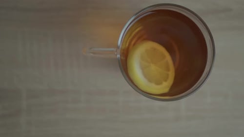 A cup of lemon tea - with a slice of citrus on it swirling in a clockwise motion - close up