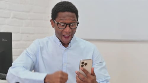 Young Man Celebrates Good News on Smart Phone