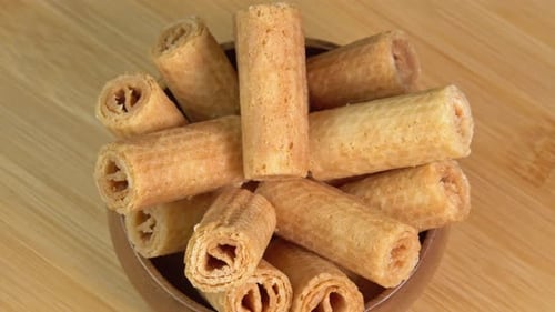 Die
knusprige Waffelröhre ohne Füllung dreht sich in einer Holzschale. Köstliches Waffelbrötchendessert. Hausgemacht