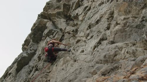 Woman Having Break and Climbing Steep Rocky Cliff