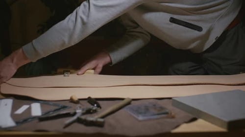 Man Shaping Leather with Tools on Table