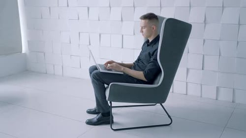 Man Using Laptop in Modern Chair