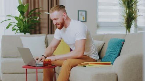 Man Working on Laptop at Home on Couch