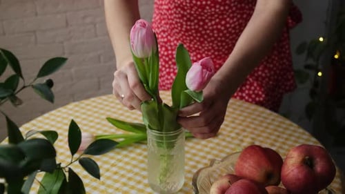 Woman Arranging Fresh Tulips in a Glass Vase