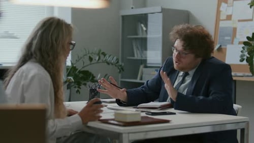 Businessman Having Conversation with Female Colleague at Office Desk