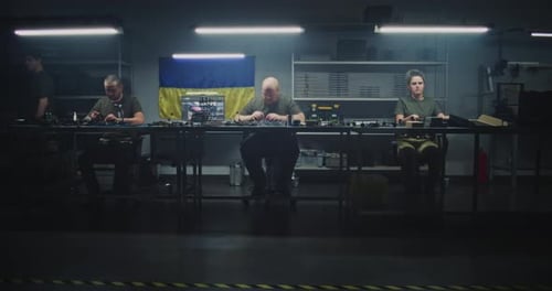 Workers Assembling Electronic Components at Workshop Table