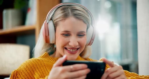 Happy woman, laughing and phone with headphones for watching movie, online streaming
