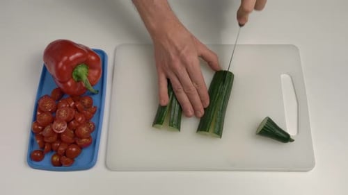 Man cutting cucumber with knife. Top down view. Amateur cook
