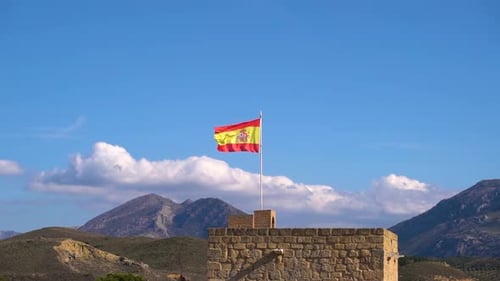 Stunning landscape scenery with mountains, blue sky and Spanish flag waving