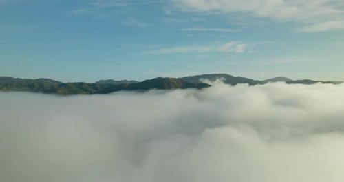 Flying through the clouds above mountain tops.