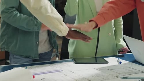 Team Huddle Over Blueprints in Office Workplace