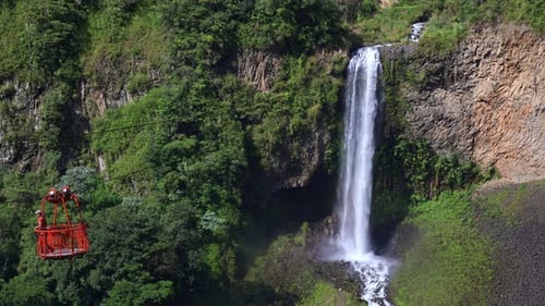 Indigenous Man Crossing in a Tarabita in Front of Manto de la Novia Waterfall, Baños de Agua Santa,