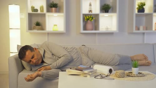 Man Sick on Couch Blowing Nose with Tissue