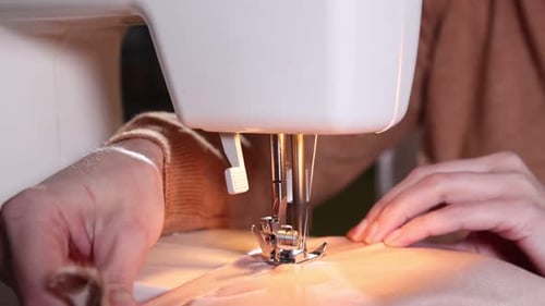 Woman sewing fabric with professional machine in workshop, closeup