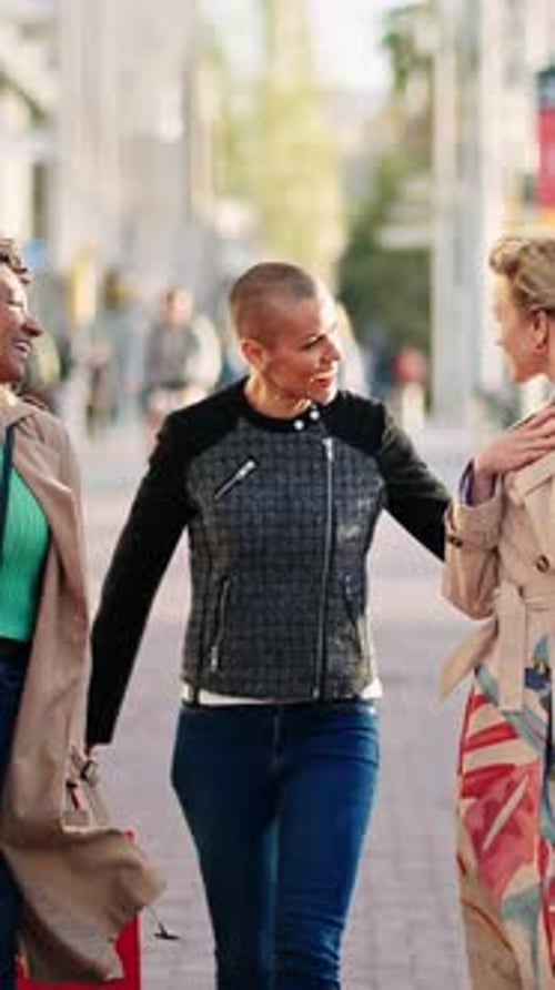Trois femmes joyeuses marchant dans la rue avec des sacs à provisions et riant ensemble après un