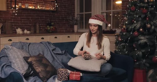 Woman in Santa Hat Unwrapping Christmas Presents