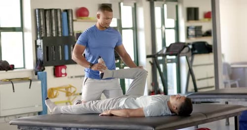 Physical therapist stretching patient's leg during rehabilitation session in clinic