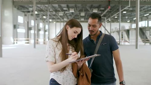 Property Owners Signing Paperwork in Empty Warehouse Adult