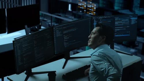 Side View Of Asian Man Having Backache While Write Code With Multiple Computer Screens In office