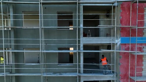 Los constructores trabajan de frente al edificio, se apoyan en el andamio