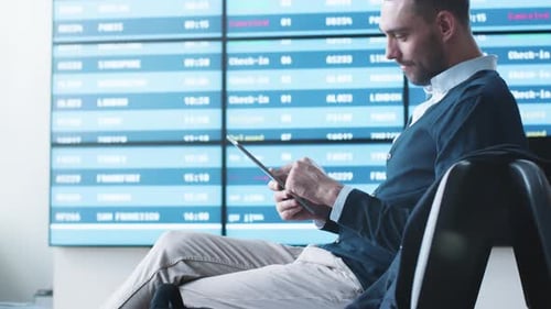 Man using Tablet while Waiting Boarding at Departure Lounge at the Airport.