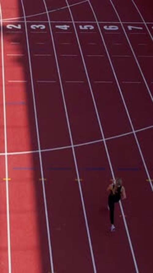 Vertical Aerial View Of Young Woman Running On Red Stadium Track