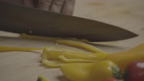 Close Up of Knife Chopping Yellow Peppers