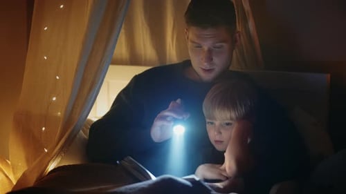 Father Reading Bedtime Story to Child with Flashlight