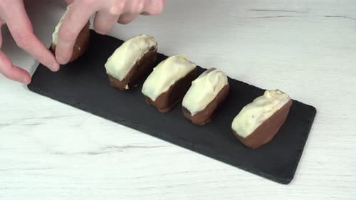 Hand puts chocolate dessert on dish for serving. The chocolate chip cookie is placed on black