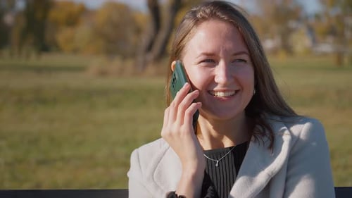 Woman Talking on Cell Phone Sitting on Bench