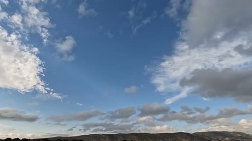 Weiße Wolken fliegen auf blauem Himmel mit Sonnenstrahlen