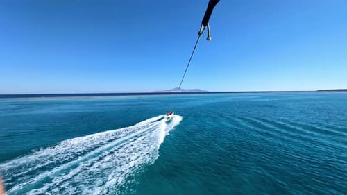 POV des Gleitens mit Fallschirm über dem wunderschönen Meer, das beim Parasailing mit dem Boot gezogen wird