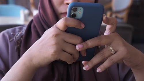 Frauen halten Smartphone in der Hand und sitzen im Café