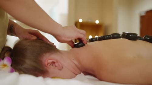 Female Spa Wellness Center Masseuse Puts Hot Stones to Client Back Woman Makes Massage Performs