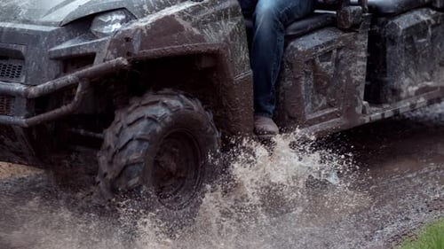 Nahaufnahme eines ATV, das in Zeitlupe durch Schlamm fährt