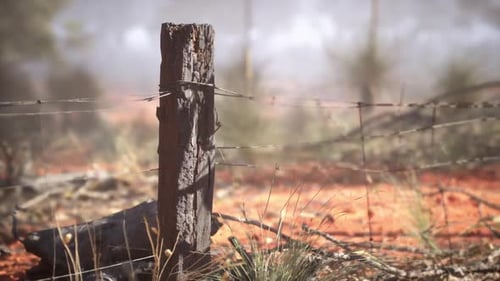Rural Farm Fence Post with Barbed Wire in Dusty Landscape