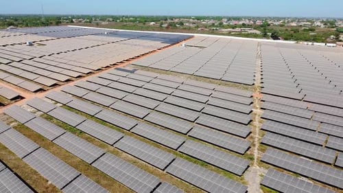 Smooth aerial panorama of entire renewable energy solar photovoltaic power plant farm with contrasti