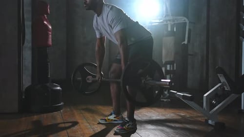 Man Lifting a Barbell in Dark, Smoky Gym