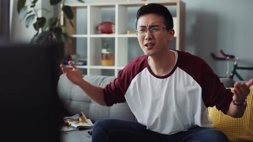 Upset Young Adult Watching Television in Living Room