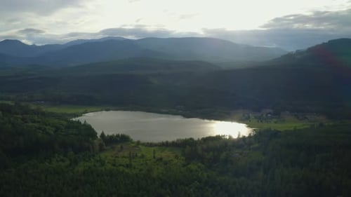 lake surrounded by evergreen trees and a forest with mountains in the background