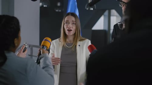 Woman Speaks at Press Conference Surrounded by Microphones