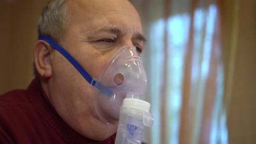 Senior Man Using Nebulizer Mask for Respiratory Treatment