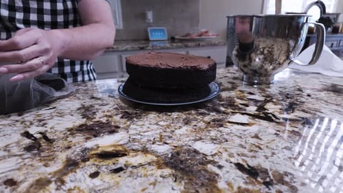 Woman Frosting Two-Layer Chocolate Cake in Kitchen