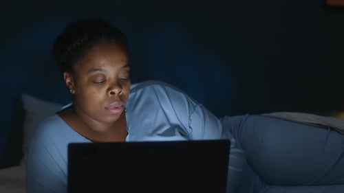 Woman Typing on Laptop in Dark Bedroom during Sleepless Night