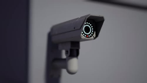 Outdoor CCTV Security Camera Mounted on Building Wall with Blurred City